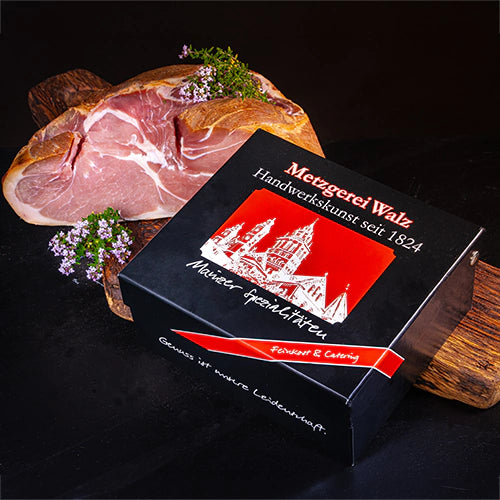 Geschenkbox „Mainzer Spezialitäten“ der Metzgerei Walz mit traditionellem Mainzer Schinken auf rustikalem Holzbrett.