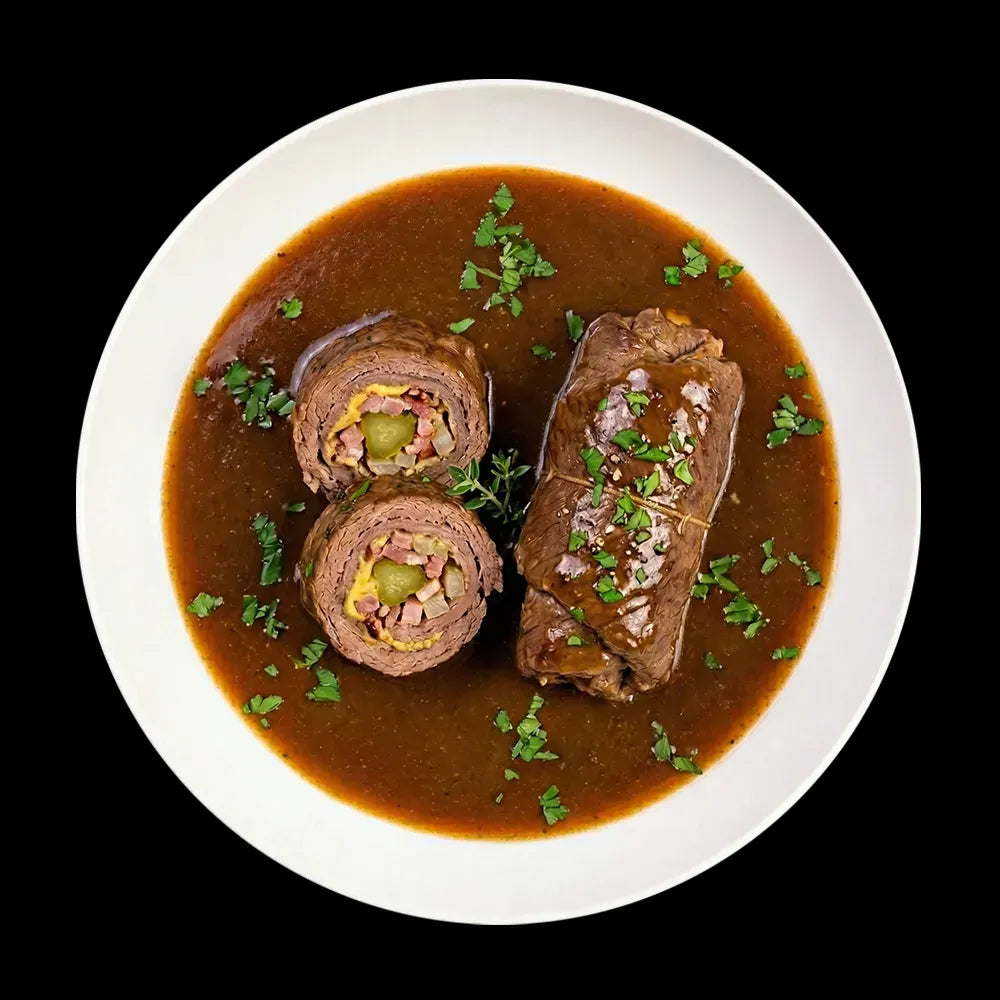 Klassische Rinderrouladen „nach Hausfrauenart“ in kräftiger Bratensoße. Eine aufgeschnittene Roulade zeigt die traditionelle Füllung aus Speck, Zwiebeln und Gewürzgurke. Ein herzhafter Genuss aus handwerklicher Herstellung der Metzgerei Walz.