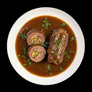Klassische Rinderrouladen „nach Hausfrauenart“ in kräftiger Bratensoße. Eine aufgeschnittene Roulade zeigt die traditionelle Füllung aus Speck, Zwiebeln und Gewürzgurke. Ein herzhafter Genuss aus handwerklicher Herstellung der Metzgerei Walz.