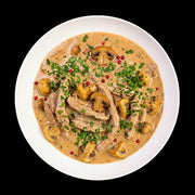 Zartes Schweinerahmgeschnetzeltes in einer cremigen Pilz-Rahmsoße. Das Gericht ist reichlich mit gebratenen Champignons, frischer Petersilie und roten Pfefferkörnern bestreut und verspricht hausgemachten Genuss wie im Restaurant.