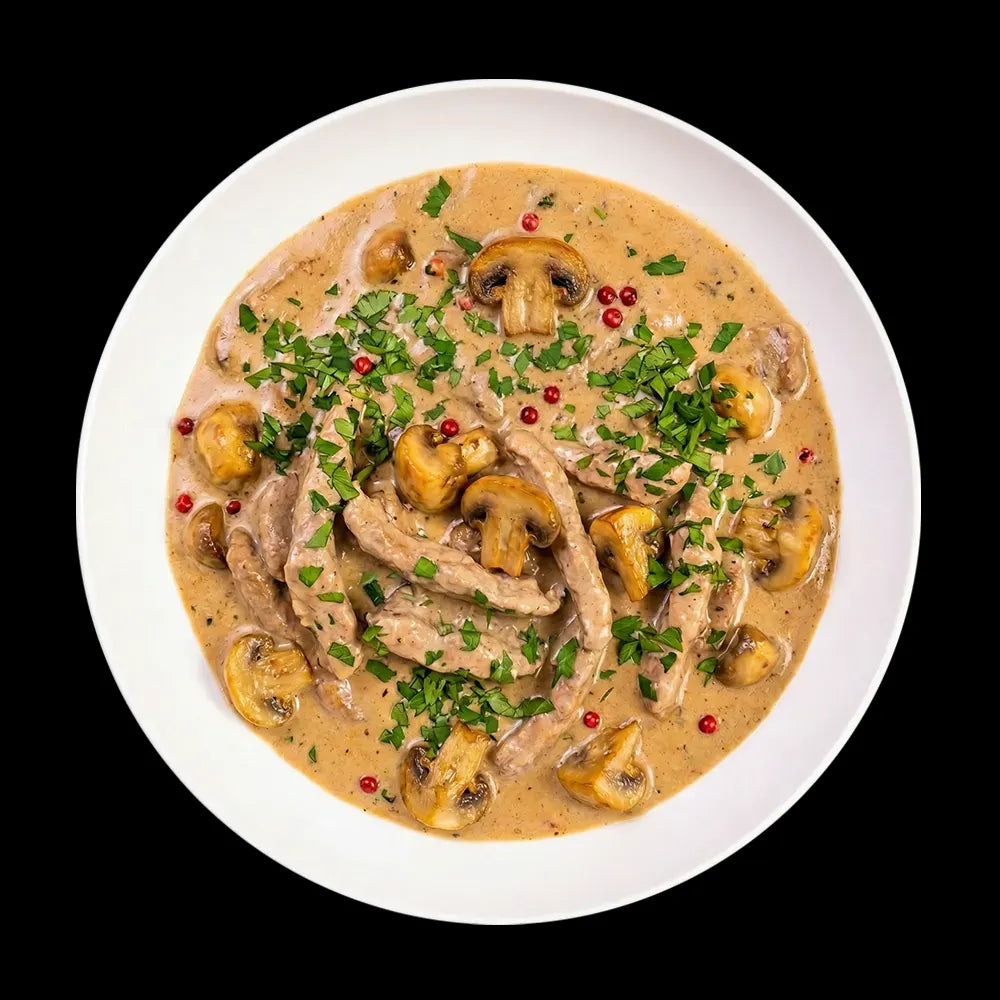 Zartes Schweinerahmgeschnetzeltes in einer cremigen Pilz-Rahmsoße. Das Gericht ist reichlich mit gebratenen Champignons, frischer Petersilie und roten Pfefferkörnern bestreut und verspricht hausgemachten Genuss wie im Restaurant.