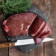 Ein großes, frisches Stück dunkle Rinderleber, fachgerecht in Scheiben geschnitten auf einer dunklen Schieferplatte präsentiert. Ein hochwertiges Naturprodukt der Metzgerei Walz, ideal für die frische Zubereitung mit Zwiebeln und Äpfeln.