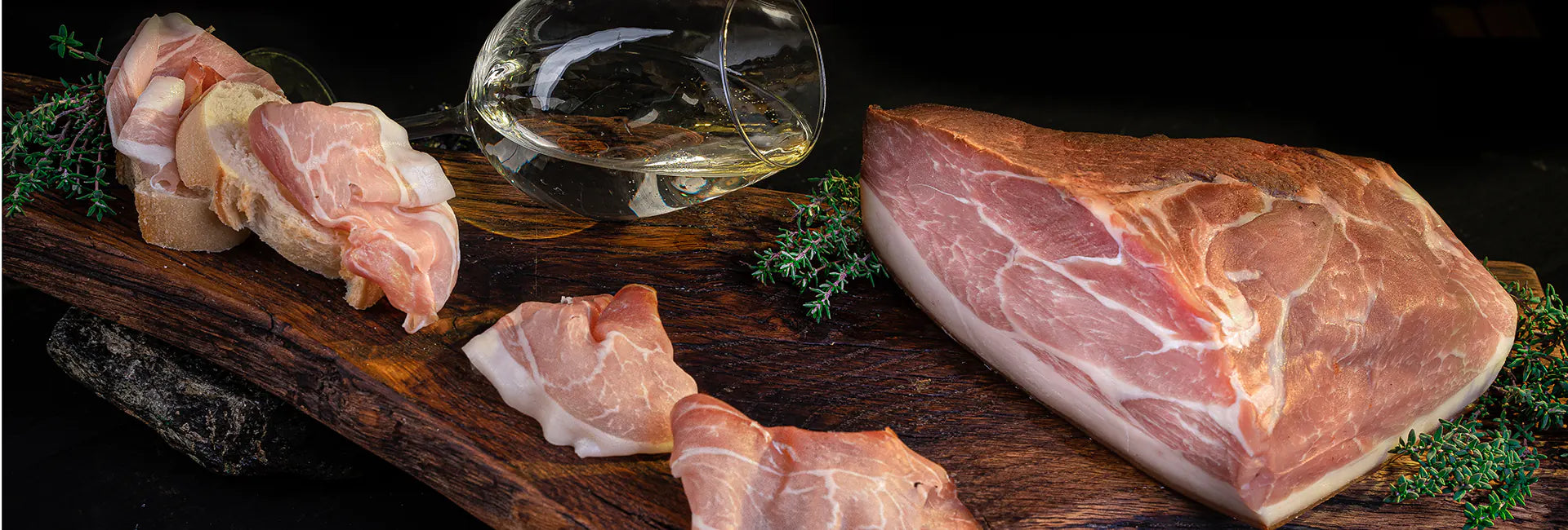 Mainzer Schinken der Metzgerei Walz auf rustikalem Holzbrett mit Weißwein, frischem Brot und Kräutern – traditionelle Schinkenspezialität aus Mainz.