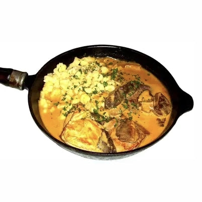 Deftige saure Nierchen in einer cremigen Rahmsoße, direkt in der gusseisernen Pfanne serviert neben einer Portion goldgelber Spätzle. Mit frischen Kräutern garniert – ein echtes Stück rheinhessische Küchentradition.