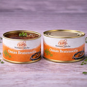 Zwei Dosen „Omas Bratensoße“ aus der Serie „Mainzer Küche“. Eine Dose ist geöffnet und präsentiert eine dunkle, kräftige Soße mit feinen Kräutern. Das warme, orangefarbene Etikett unterstreicht den traditionellen Charakter dieser wie hausgemachten Soße.