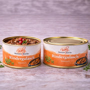 Klassisches Rindergulasch aus der „Mainzer Küche“ der Metzgerei Walz in der Vorratsdose. Die Abbildung zeigt saftige, mürbe Fleischstücke in einer aromatischen Soße, appetitlich angerichtet mit roten Beeren und Kräutern. Traditionelles Handwerk für die schnelle, hochwertige Küche.
