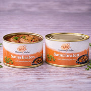 Verzehrfertiger Sauerbraten nach Hausfrauenart aus der Mainzer Küche. In der geöffneten Dose sind zarte Fleischscheiben in einer dunklen, glänzenden Soße mit Gewürzkörnern und Kräutern zu sehen. Ein herzhaftes Fertiggericht in Metzgerqualität.